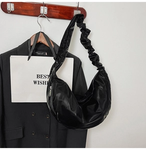 Detailed close-up of a black ruched shoulder strap on a sleek nylon crescent bag