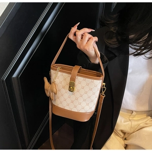 Détail du sac seau beige avec monogramme vintage et fermoir doré porté à l'épaule