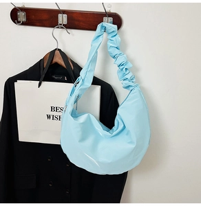 Close-up of light blue crescent shoulder bag with ruched handle and metallic zipper