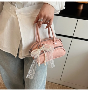Detail of pink mini bag with lace pearl bow and litchi texture on a casual outfit