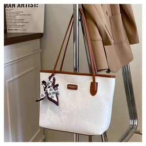Detail of white snakeskin texture tote bag with brown leather straps and silk scarf