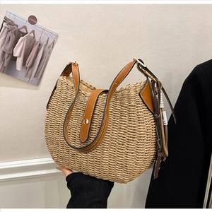 Detailed texture of hand-woven straw tote bag with brown leather strap and tassel detail