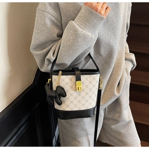 Détail du sac seau contrasté avec imprimé lettres et breloque animal sur un mannequin