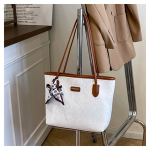 Detail of white snakeskin tote bag with brown straps and silk scarf on display