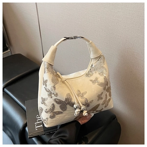 Detail of cream hobo bag with silver sequin butterflies and metallic ball charms