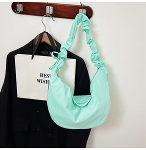 Detail of mint green crescent bag with ruched shoulder strap and bow tie accent