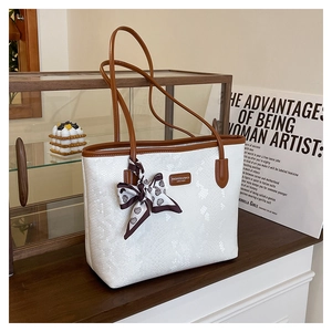 Detail of white snakeskin tote with brown leather handles and heart-patterned silk scarf