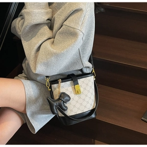 Détail du sac seau bicolore avec imprimé lettres et breloque chien en cuir sur escalier