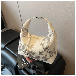 Detail of white leather handbag with silver sequin butterflies and metallic handle