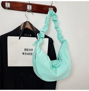 Detail of mint green crescent bag featuring unique ruched straps and a metal zipper