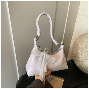Détail du sac violet clair avec poignée tressée, nœud en dentelle et breloques en perles