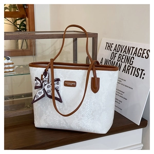 Detail of white snakeskin tote bag with brown straps and decorative silk scarf