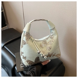 Close-up of light green hobo bag featuring sequin butterfly embroidery and metal hardware