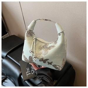 Detail of light green bag showing silver sequin butterfly patterns and metal bead drawstring