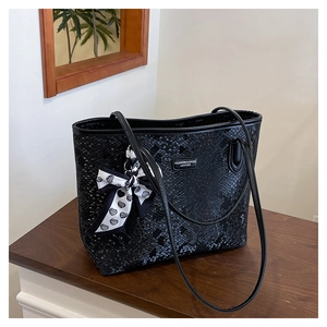 Detail of black snakeskin texture tote bag with elegant polka dot heart scarf accent