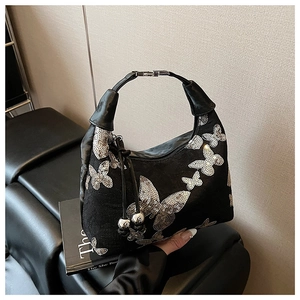 Close-up of sequined butterfly patterns and metal ball drawstring on a black crescent bag