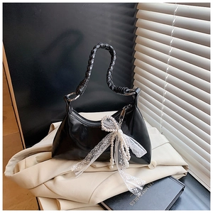 Détail du sac demi-lune noir avec poignée tressée et nœud en dentelle de perles