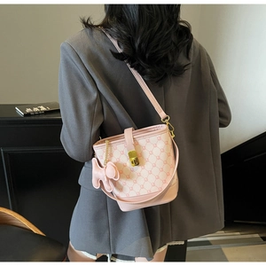 Détail du sac seau rose à monogramme avec fermoir doré et breloque chien sur veste grise