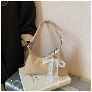 Détail du sac à main kaki clair avec poignée tressée et nœud en dentelle et perles