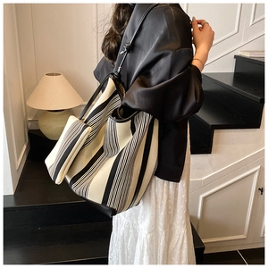 Detail of a large black and white striped tote bag and small pouch on a model