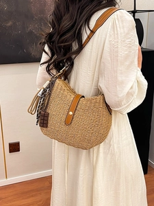 Handcrafted straw bucket bag with brown leather strap and chocolate charm in a warm room