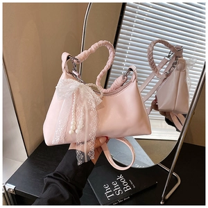 Détail du sac dumpling rose avec perles et pendentif nœud en dentelle blanche élégant