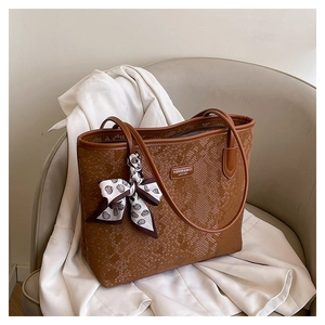 Detail of retro brown tote bag with snakeskin texture and decorative heart print scarf
