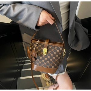 Détail du sac seau bicolore avec motif monogramme vintage et fermoir doré chic