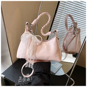 Détail du sac à main rose avec poignée tressée, nœud en dentelle et accessoires de perles