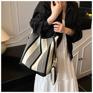 Detail of black and white striped canvas tote bag with matching pouch and leather trim