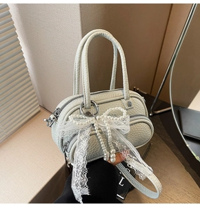 Detail of light green mini bag with lace bow and pearl charm on lychee leather texture