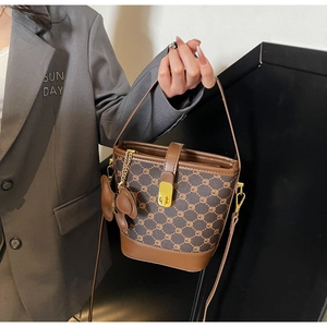 Détail du sac seau bicolore avec motifs géométriques et fermoir en métal doré de luxe