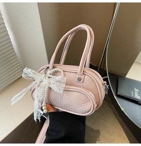 Detail of light pink pebble leather mini bag with pearl chain and lace bow charm