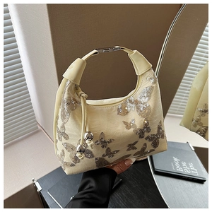 Close-up of sparkling silver sequin butterfly patterns on a cream chic shoulder bag