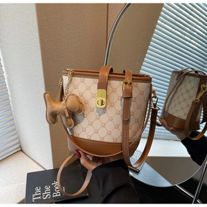 Détails du sac seau en toile avec garniture en cuir marron et breloque chiot