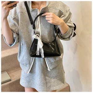 Détail du sac lune noir brillant avec chaîne de perles et ruban de dentelle