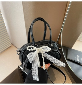 Detailed macro view of black pebbled leather texture with lace bow and pearl charms
