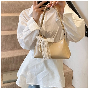 Détail du sac beige avec poignée tressée et charm perle en nœud de dentelle chic
