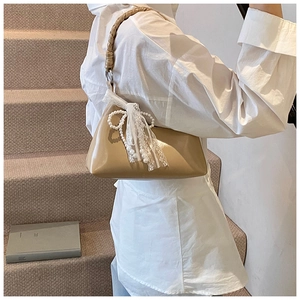 Détail du sac en laque kaki avec décoration de nœud en dentelle et perles blanches