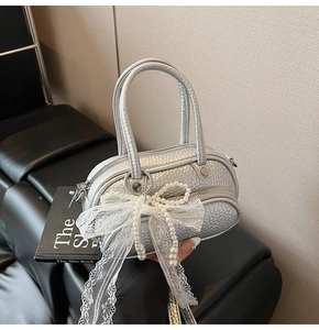 Detail of silver textured leather mini bag with white lace bow and pearl handle
