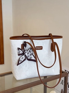White snakeskin tote bag with brown leather straps and a heart pattern decorative scarf