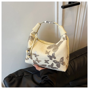 Macro detail of beige sequined butterfly pattern and metal ring handle on handbag