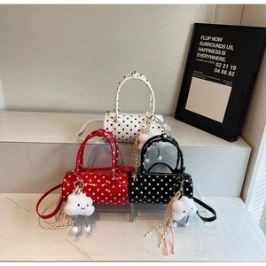 Cylindrical polka dot handbag detail with plush cloud charms and adjustable straps