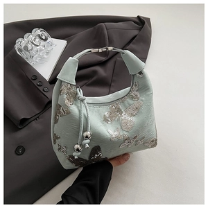 Detailed view of mint green shoulder bag featuring sequin butterfly embroidery and metal bead tassel