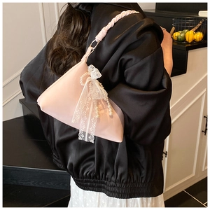 Détail du sac rose avec un nœud en dentelle blanche et des perles décoratives élégantes
