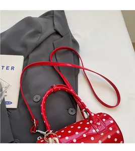 Detailed shot of red polka dot cylinder bag placed on a grey suit with a book