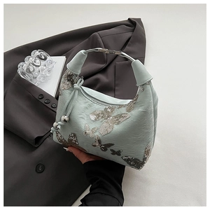 Detail of mint green bag with sequined butterfly patterns and silver metal ring handle