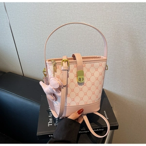 Détails du sac seau rose avec motif monogramme, fermoir doré et pendentif chiot