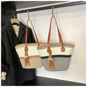 Detail of woven straw tote bags with leather straps and cute rabbit charm accessories
