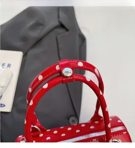 Detailed shot of comfortable red polka dot handle with sturdy metal buckle on barrel bag